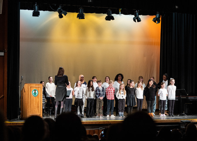 groups of kids standing on a stage in a school auditorium